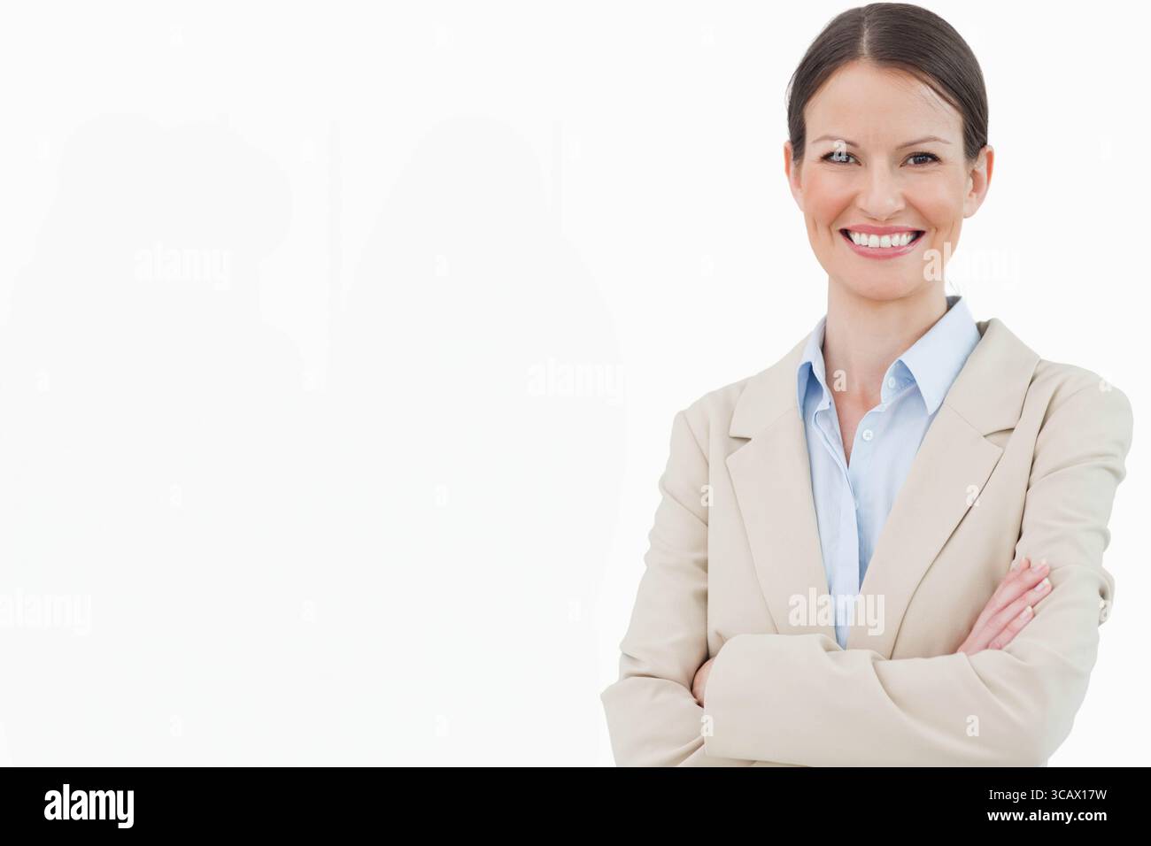 Geschäftsfrau, die mit überkreuzten Armen im Studio steht, trägt einen beigen Blazer und eine blaue Bluse, Kopierraum Stockfoto