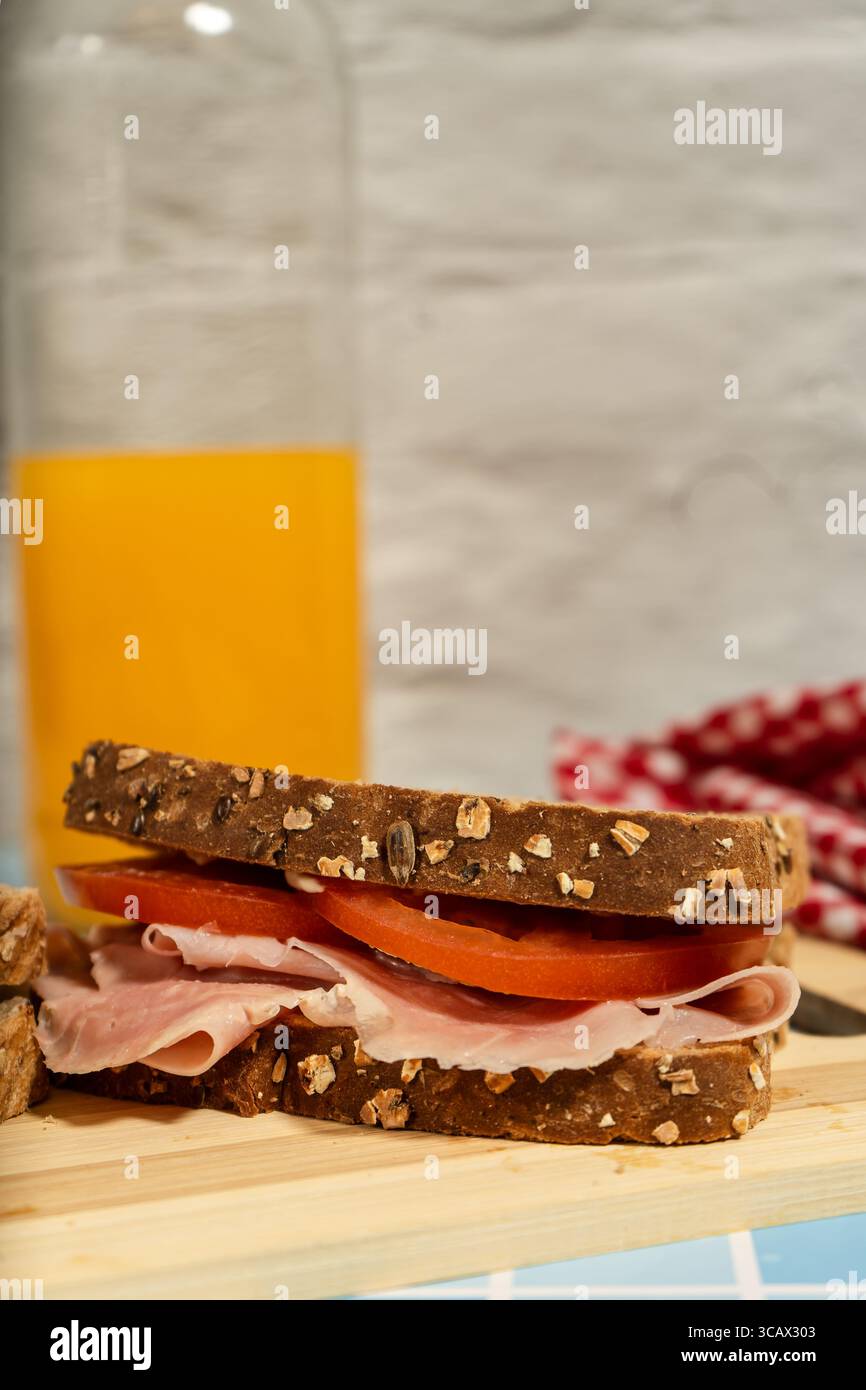 Zwei frische Sandwiches auf Holzbrett mit einem Glas und einer Flasche Saft Stockfoto
