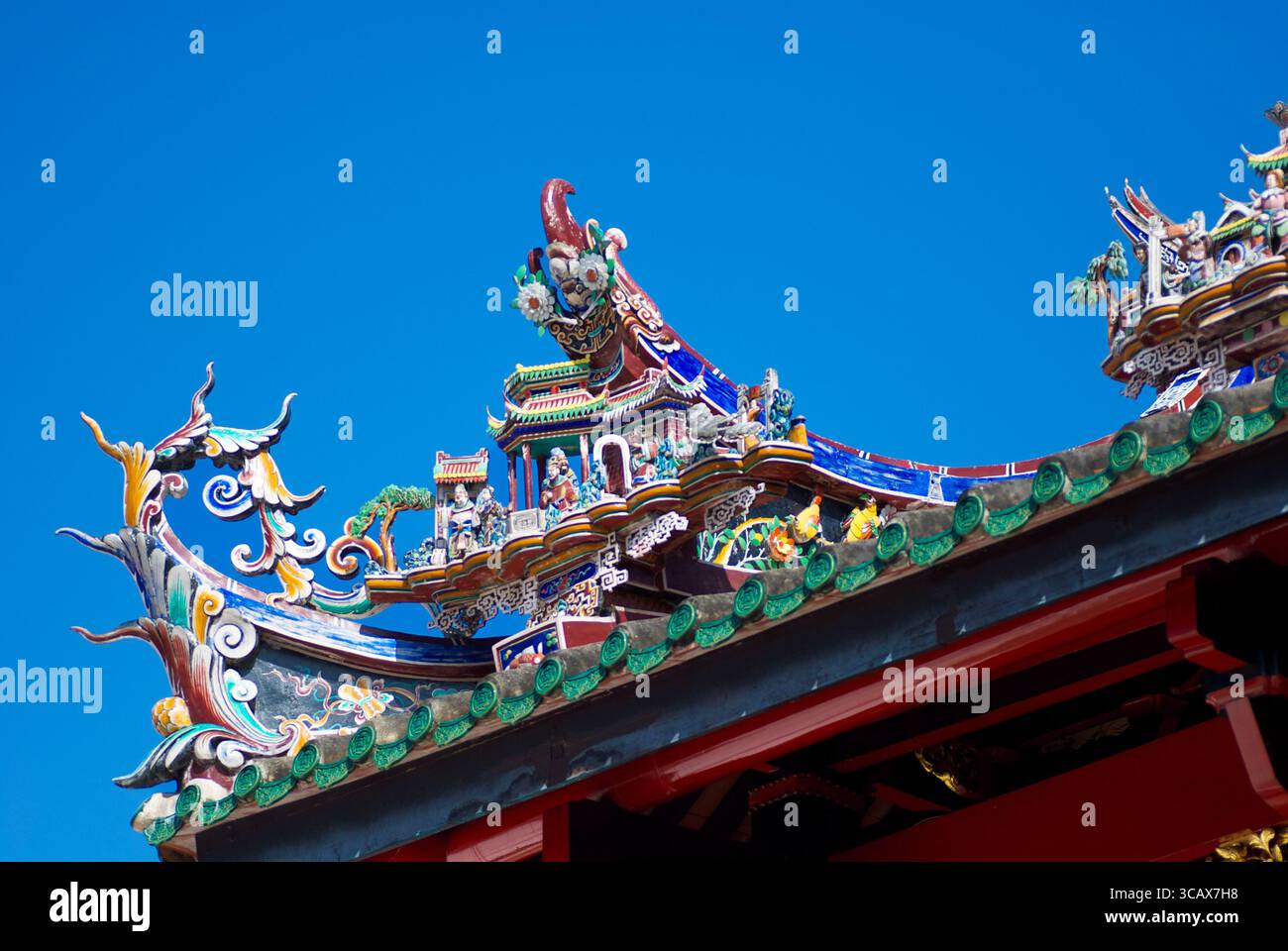 Kompliziertes chinesisches Tempeldach mit bunten Figuren und mythischen Kreaturen vor dem blauen Himmel Stockfoto