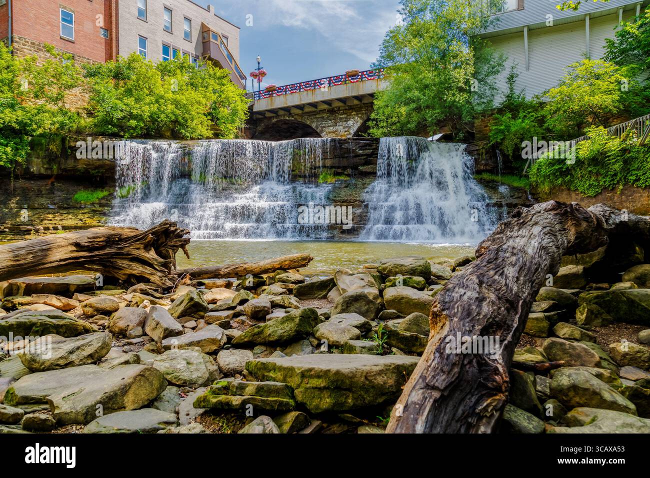 Chagrin Falls, Ohio - 15. Juni 2017: Ein malerischer Blick auf den Wasserfall, der die Felsen hinunterstürzt, mit einer Brücke im Hintergrund. Stockfoto