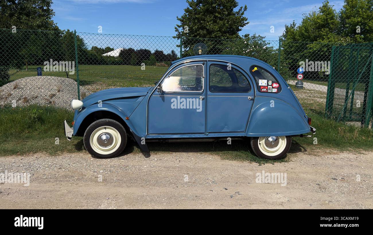 Ein klassischer hellblauer Citroën 2CV, ein legendärer Oldtimer, parkt auf einem Schotterweg. Stockfoto