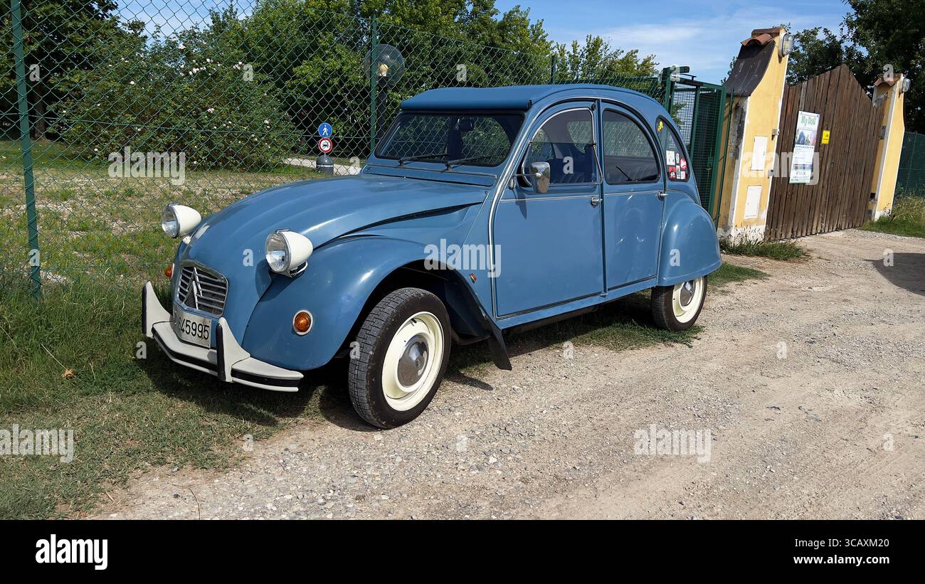 Ein klassischer hellblauer Citroën 2CV, ein legendärer Oldtimer, parkt auf einem Schotterweg. Stockfoto