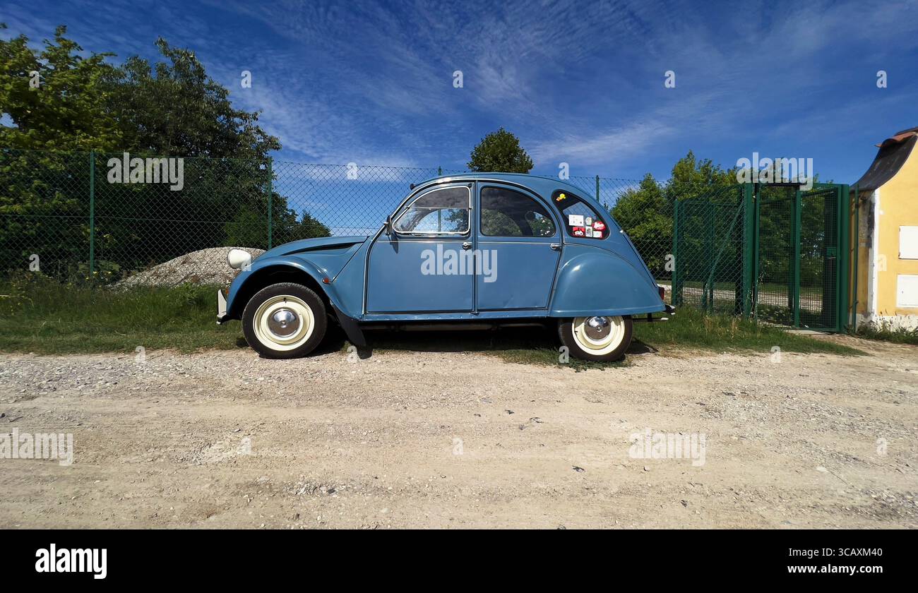 Ein klassischer hellblauer Citroën 2CV, ein legendärer Oldtimer, parkt auf einem Schotterweg. Stockfoto