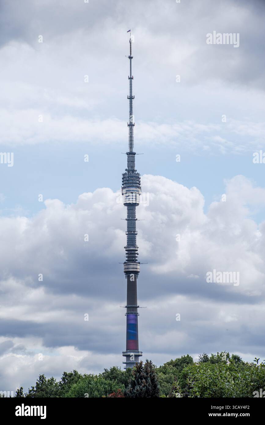 Der Ostankino-Turm in Moskau, Russland, steht hoch vor einem bewölkten Himmel mit üppig grünen Bäumen am Fuß Stockfoto