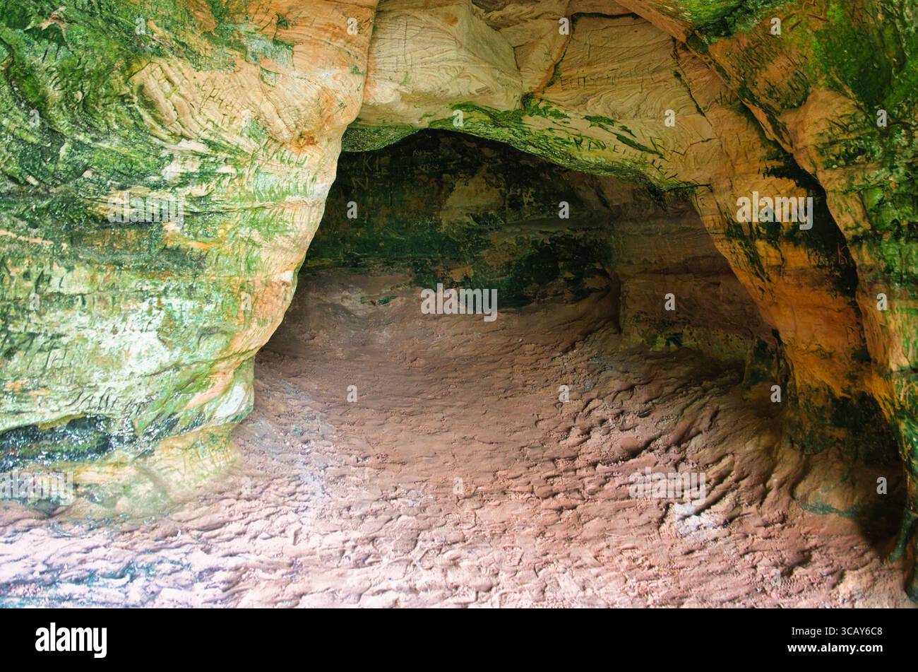 Farbenfrohe Sandsteinhöhle mit Moos und strukturierten Wänden Stockfoto