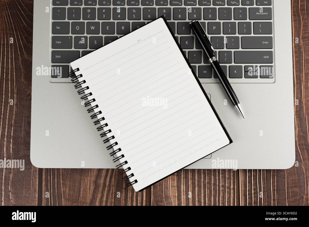 Ansicht von oben auf leerem Notizblock und Stift auf dem Laptop Stockfoto