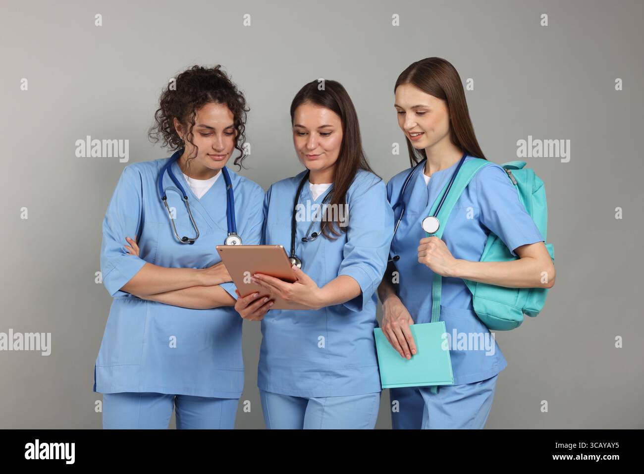 Gruppe von Medizinstudenten mit Tablette auf hellgrauem Hintergrund Stockfoto