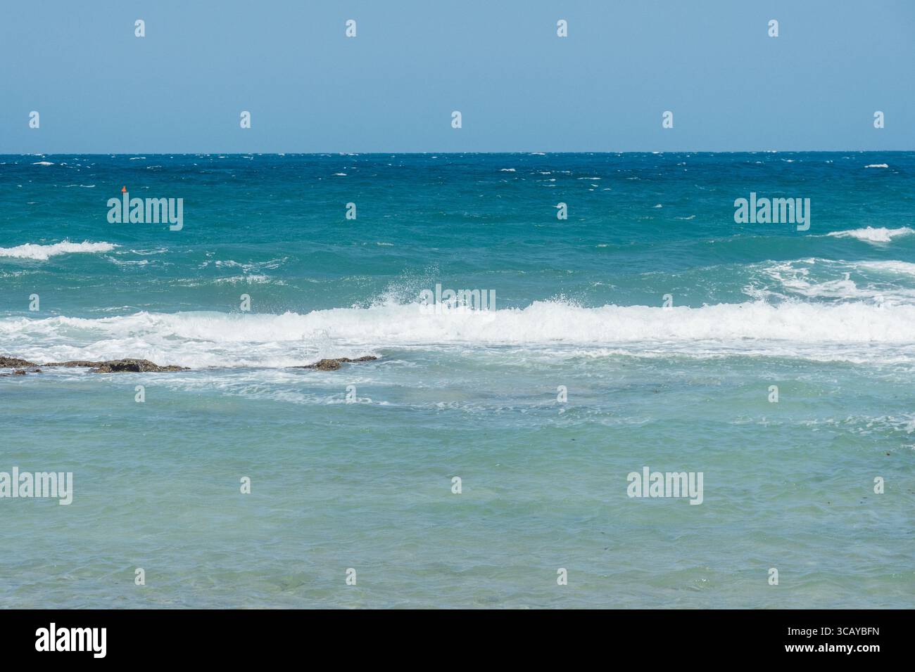 Malerischer Blick auf die Wellen, die unter einem klaren blauen Himmel an die Küste stürzen. Eine ruhige Meereslandschaft, die die Schönheit der Natur und das offene Meer einfängt Stockfoto