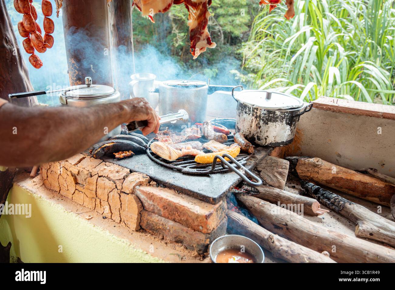 Typische Speisen aus Santander, Kolumbien, einschließlich Chorizo, Schweinebauch und Blutwurst, Grillen auf einem rustikalen Holzofen. Authentische ländliche Küche Stockfoto