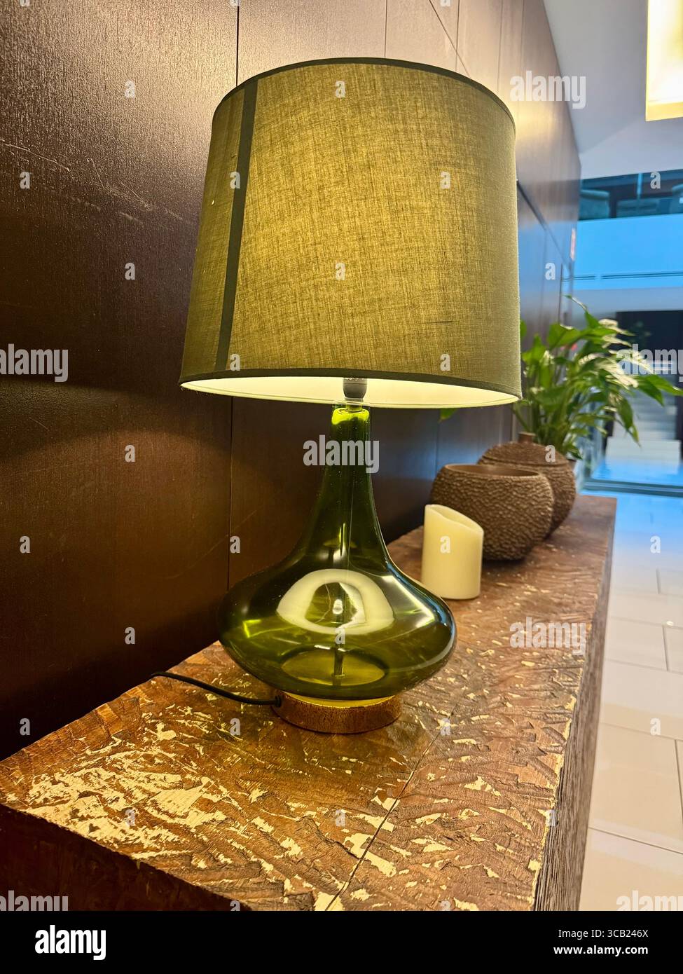 Moderne Tischlampe aus grünem Glas auf Marmoroberfläche im modernen Hotel im Furnas Octant mit dekorativen Pflanzen und dezenter Beleuchtung. Stockfoto