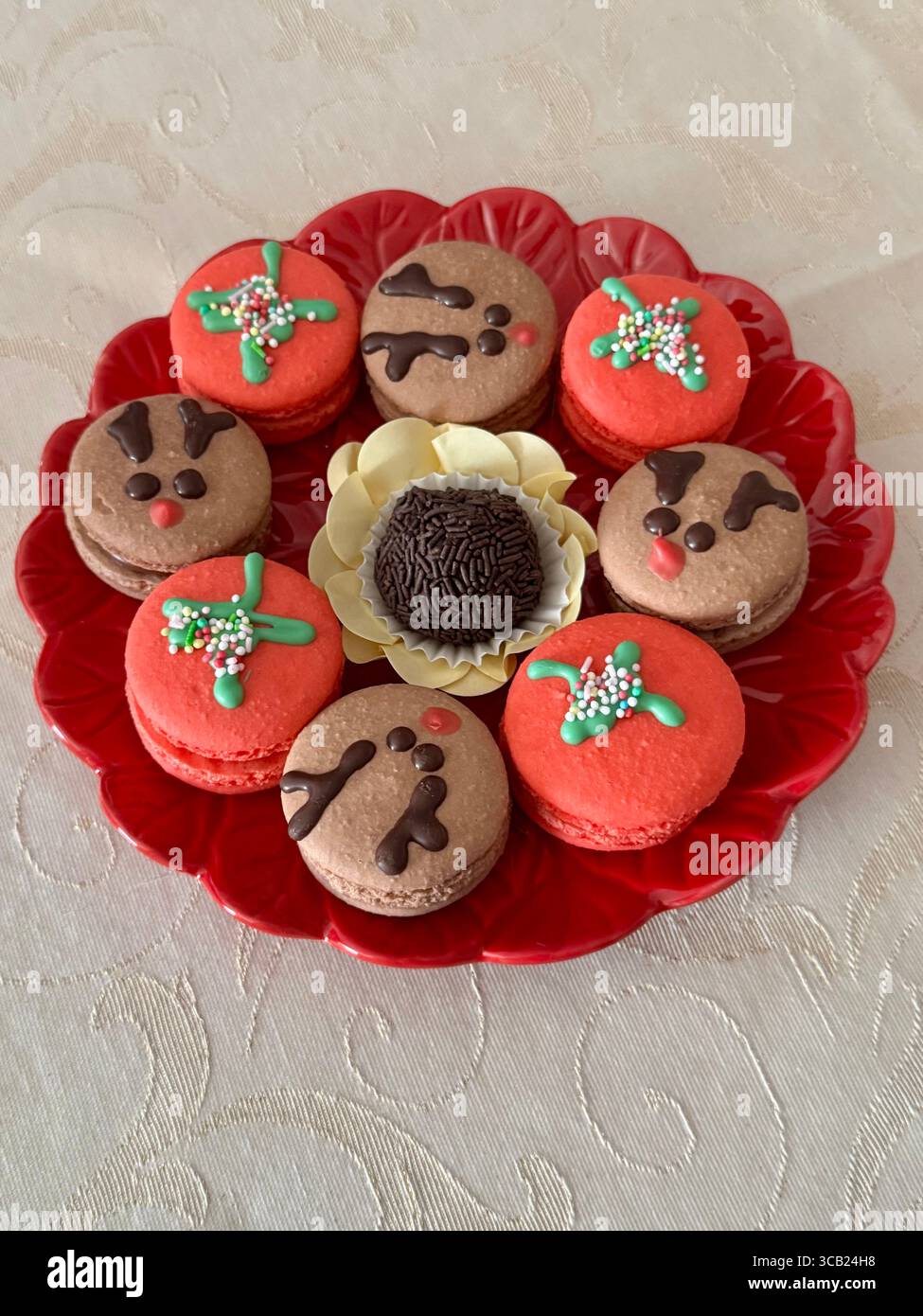 Festliche Macarons mit Weihnachtsmotiven auf einem roten Teller, perfekt für Feiertage. Stockfoto