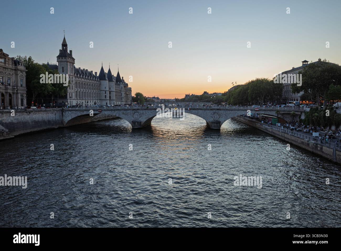 Die historische Brücke Pont Neuf überspannt die seine in Paris, Frankreich, mit einem Boot, das bei Sonnenuntergang vorbeifährt. Stockfoto