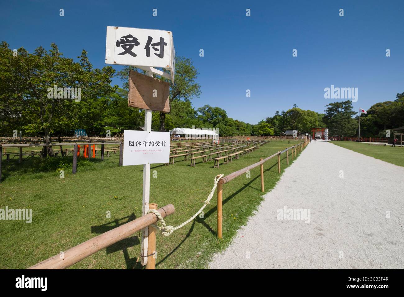 Ein klarer Tag in einem geräumigen Park mit Holzzäunen und japanischen Schildern. Die lebhafte grüne Landschaft und der blaue Himmel schaffen eine ruhige Atmosphäre, Kyoto Stockfoto