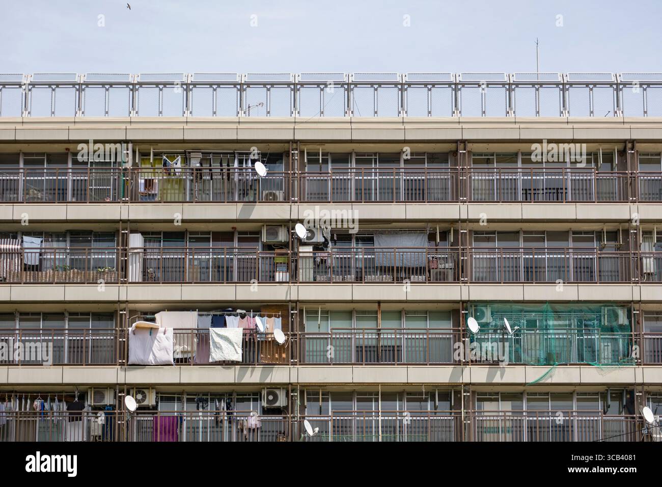 Ein mehrstöckiges städtisches Apartmentgebäude mit Balkonen und Wäschetrockner. Das Bild zeigt eine typische Wohnfassade, die urbanes Leben vermittelt Stockfoto