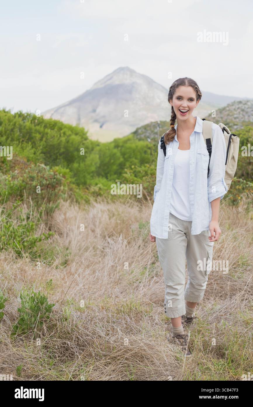 Frau, die auf einem Hügel mit Rucksack läuft, Cargo Hosen und Wanderstiefel trägt, Kopierraum Stockfoto