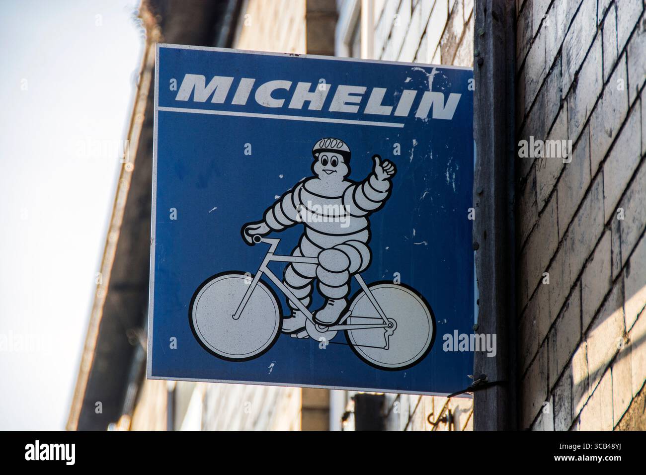 Der Michelin-Mann (Bibendum) ist dargestellt, wie er mit dem Fahrrad fährt und einen Daumen nach oben zeigt, was darauf hindeutet, dass der Laden Michelin-Fahrradreifen verkauft oder betreut Stockfoto