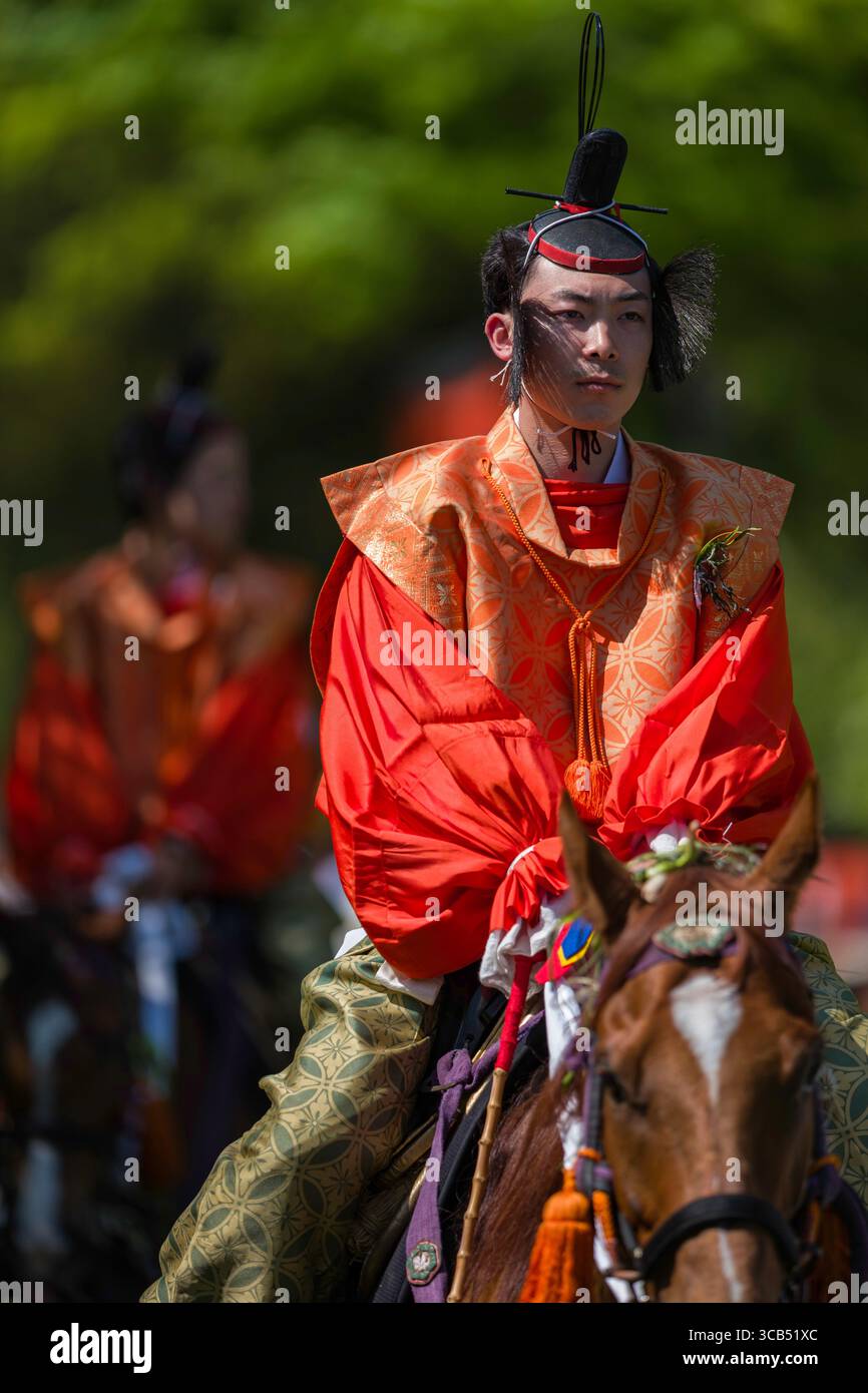 Prozession der Reiter zu Pferd während des Kamo Kurabeum Festivals am Kamigamo-Schrein, mit lebendigen Farben und historischen Kostümen, Kyoto, Japan Stockfoto