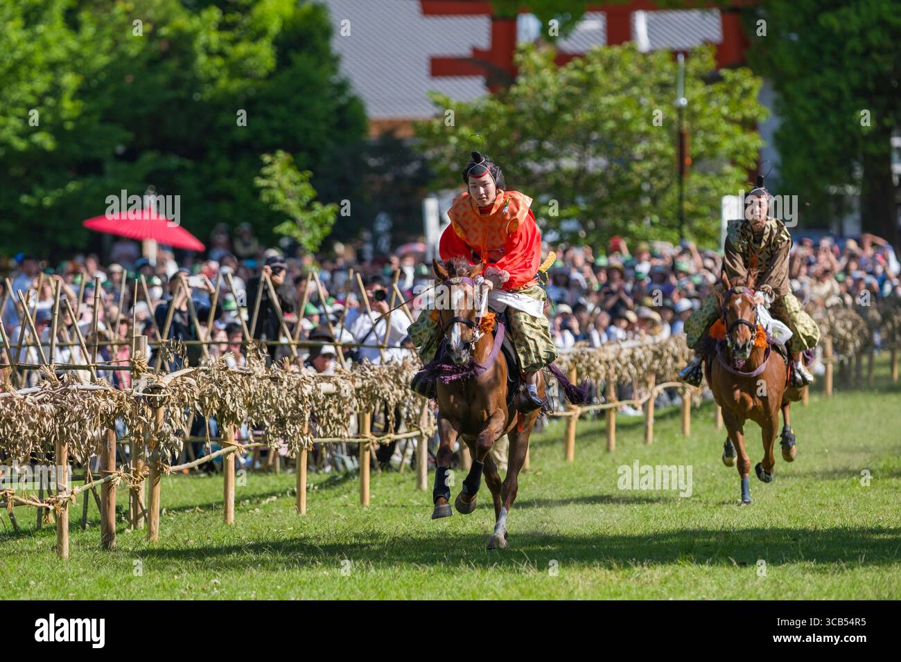 Lebendige Szene traditioneller japanischer Pferderennen mit Fahrern in historischen Kostümen während des Kamo Kurabeum Festivals im Kamigamo-Schrein in Kyoto Stockfoto