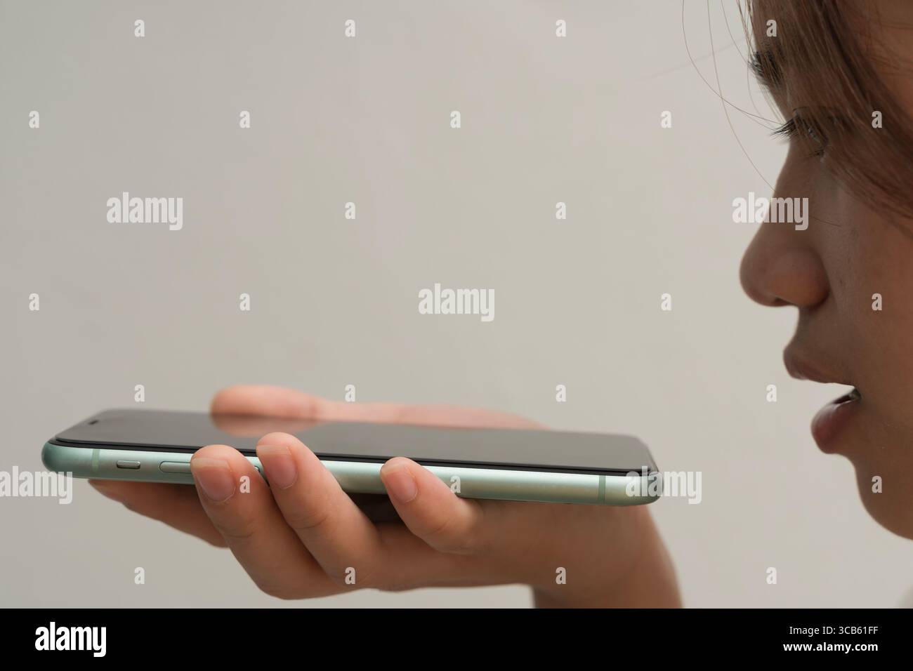 Nahaufnahme einer jungen Frau, die per Sprachbefehl oder digitalem Assistenten in das Smartphone spricht. Konzept der intelligenten Technologie, KI-Interaktion, Freisprecheinrichtung Stockfoto