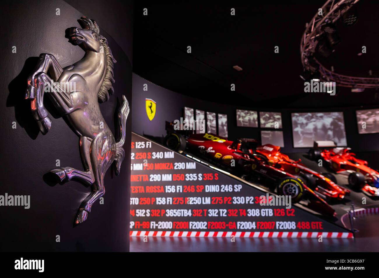 Ferrari Formel-1-Museum mit roten Rennwagen, Chrom-Emblem und historischen F1-Grafiken, die die italienische Renngeschichte zelebrieren Stockfoto