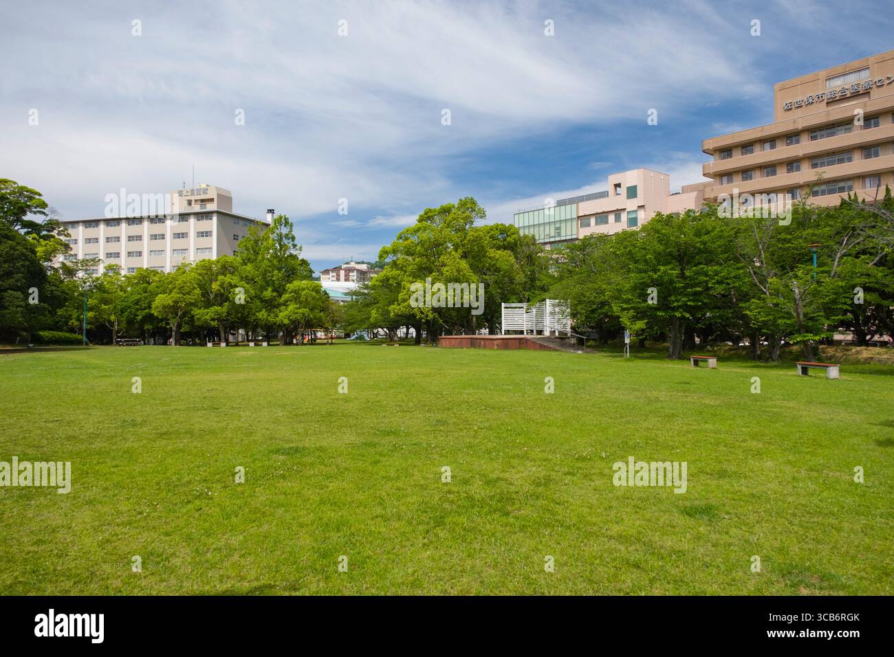 Sasebo City Park, umgeben von modernen Gebäuden unter einem ruhigen blauen Himmel, bietet eine friedliche urbane Oase. Sasebo, Nagasaki, Kyushu, Japan Stockfoto