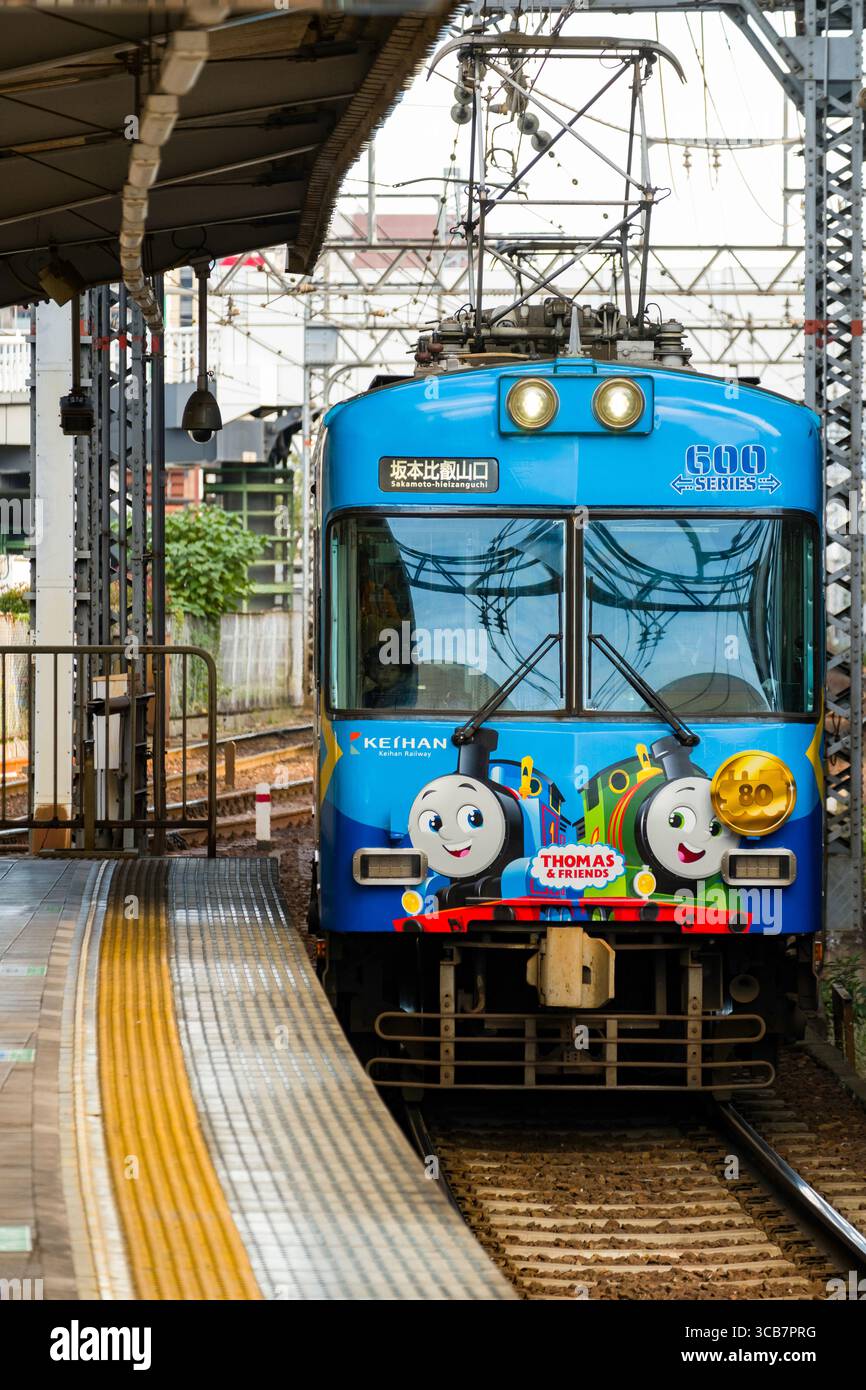 Ein bunter Zug nach Thomas der Panzermaschine, der am Bahnsteig von Biwako-Hamaotsu ankommt und von Eisenbahnbauten umgeben ist. Stockfoto
