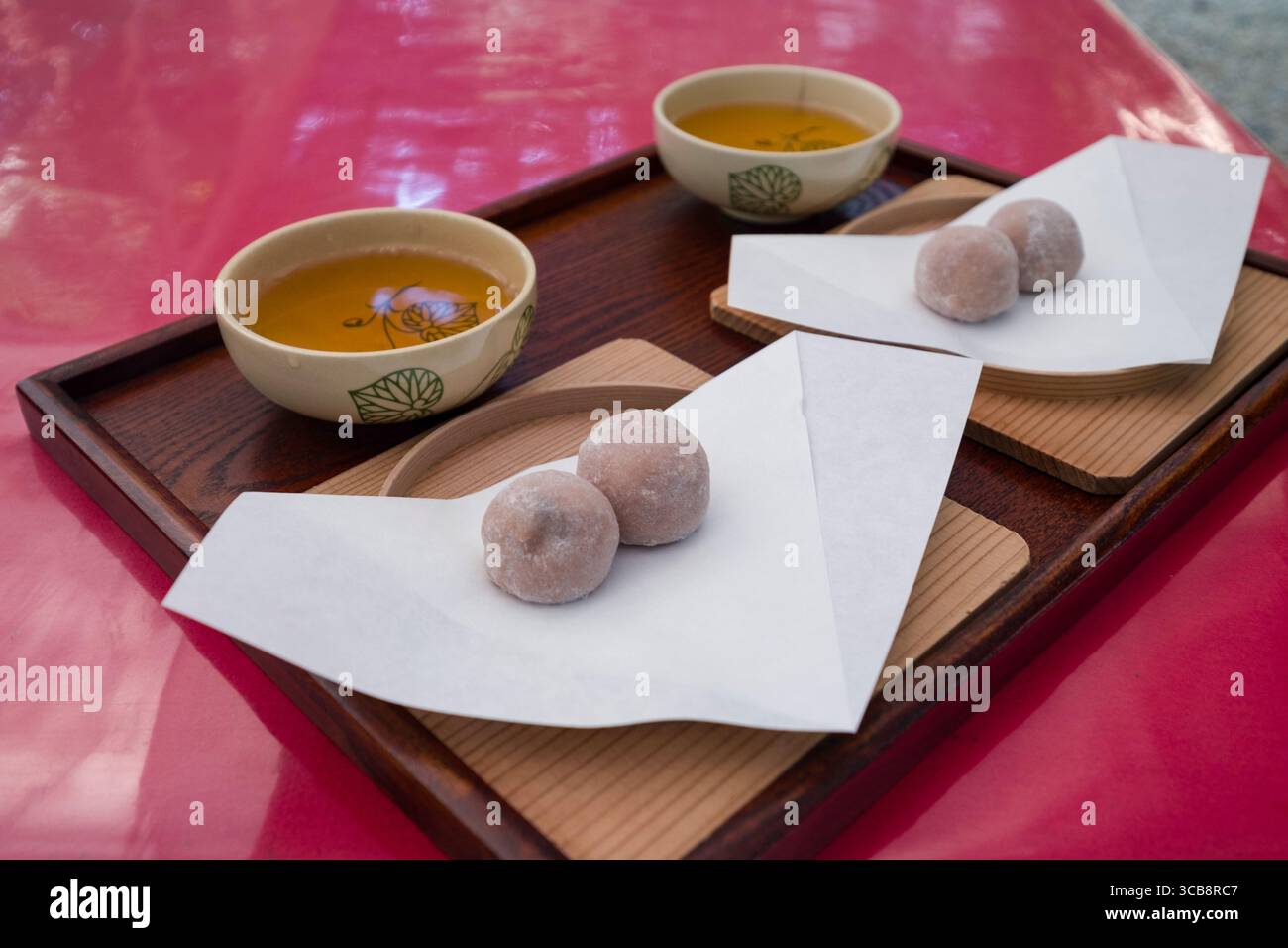 Eine köstliche Arrangement aus Matcha-Tee und japanischen Mochi-Affenreiskuchen, die auf einem Holztablett serviert werden, mit traditioneller japanischer Küche Stockfoto