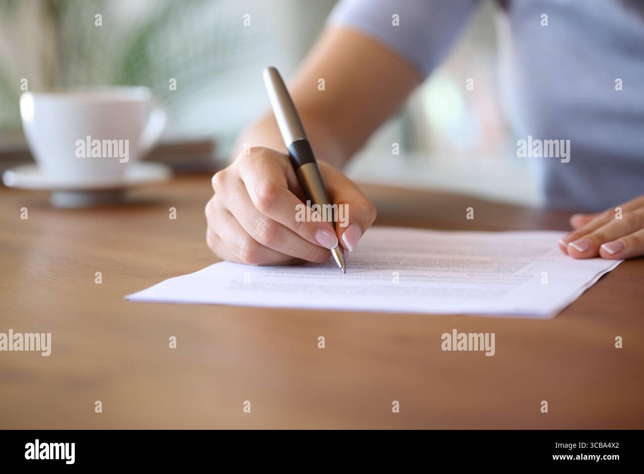 Nahaufnahme eines Hausbesitzers, der zu Hause einen Papiervertrag mit einem Stift auf einem Holztisch unterzeichnet Stockfoto