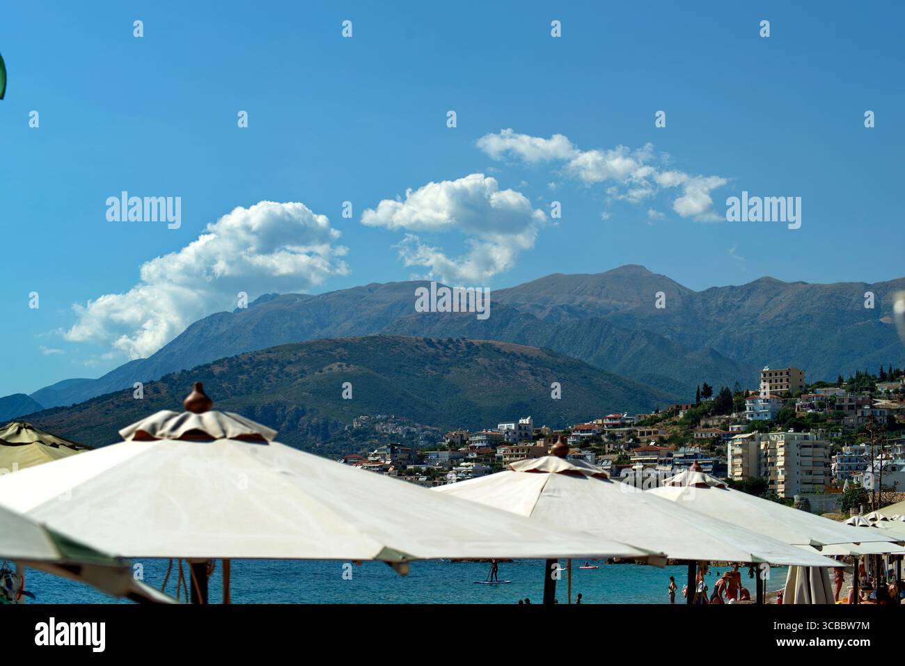 Ombrelloni contro il Mare e la costa rocciosa ad Himara in Albanien Stockfoto