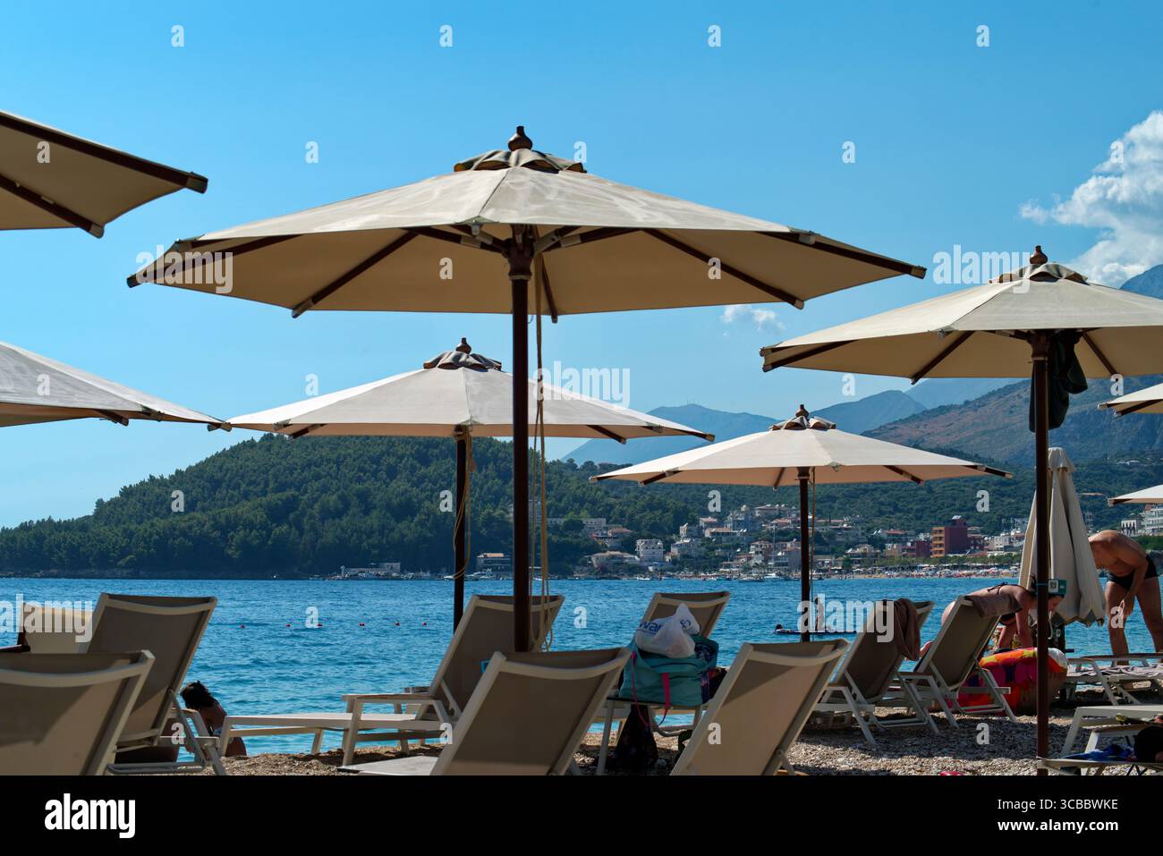 Ombrelloni contro il Mare e la costa rocciosa ad Himara in Albanien Stockfoto
