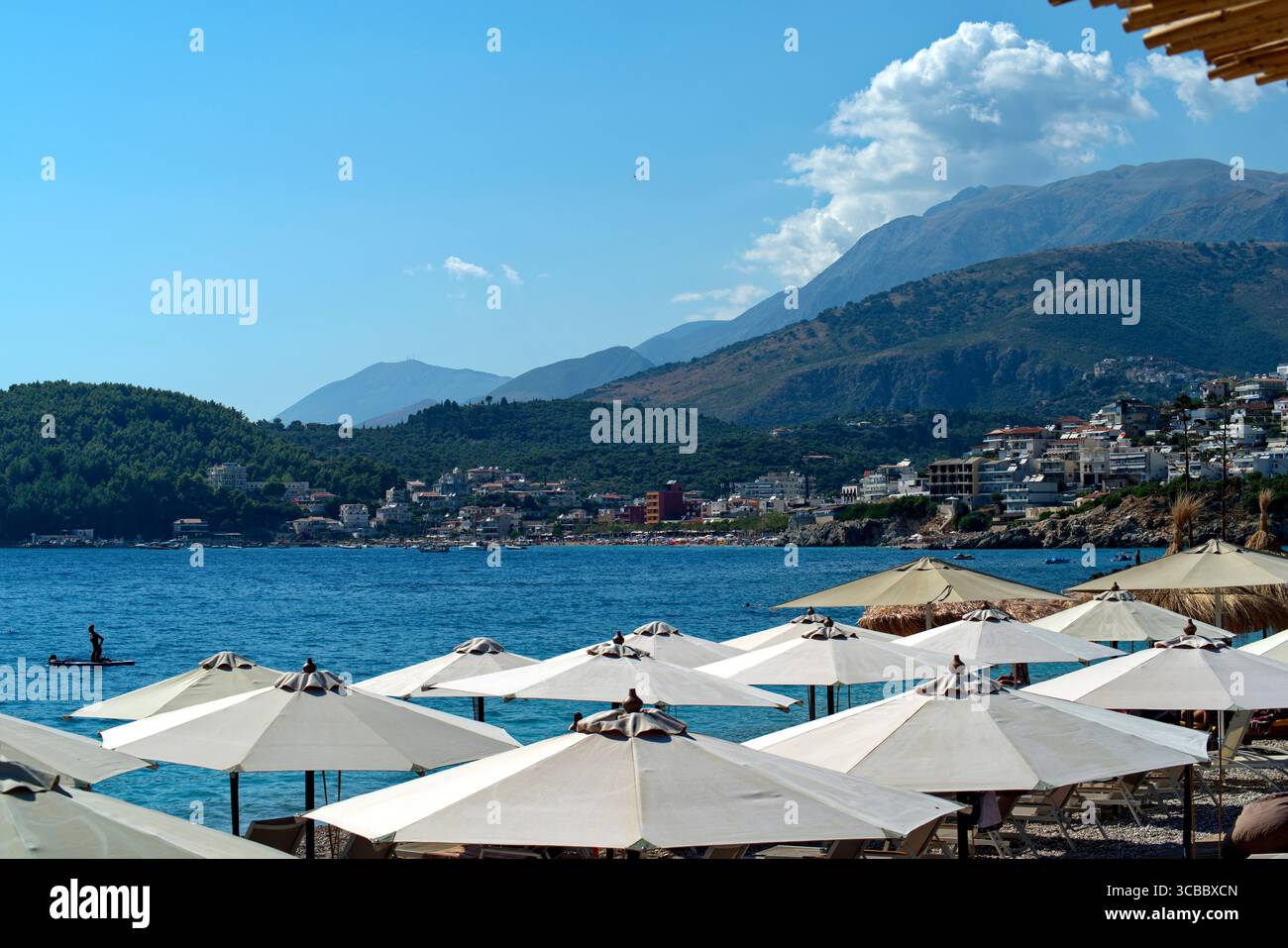 Ombrelloni contro il Mare e la costa rocciosa ad Himara in Albanien Stockfoto