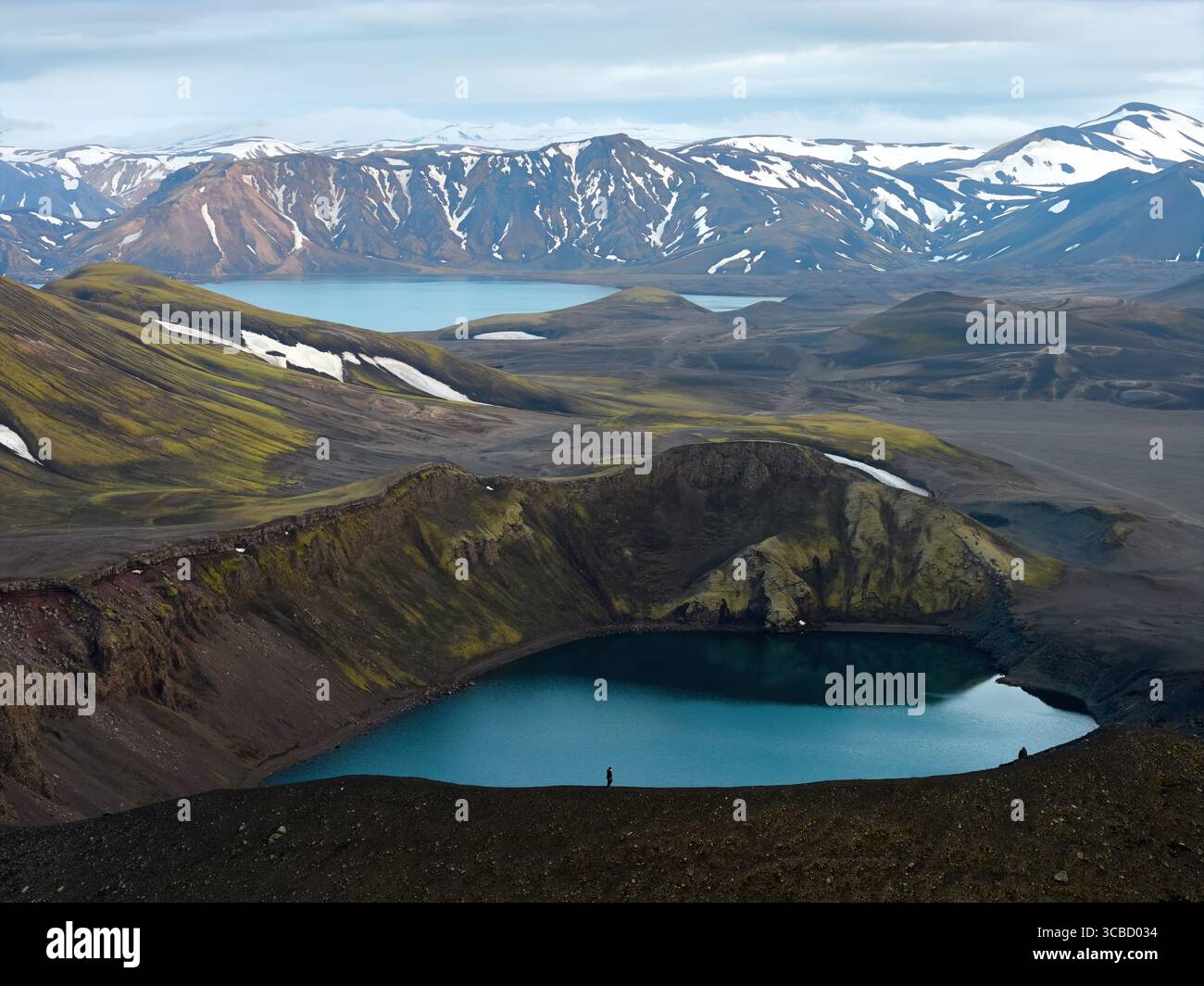 Wanderer, der einen atemberaubenden Kratersee im isländischen Hochland betrachtet Stockfoto