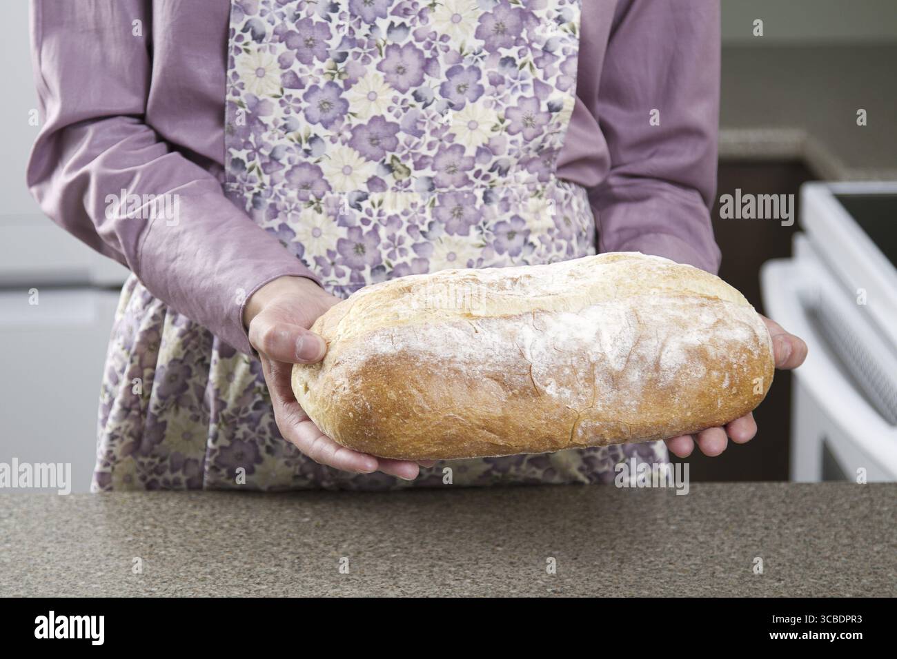 Eine Frau mit einer Schürze und einem Brotlaib Stockfoto
