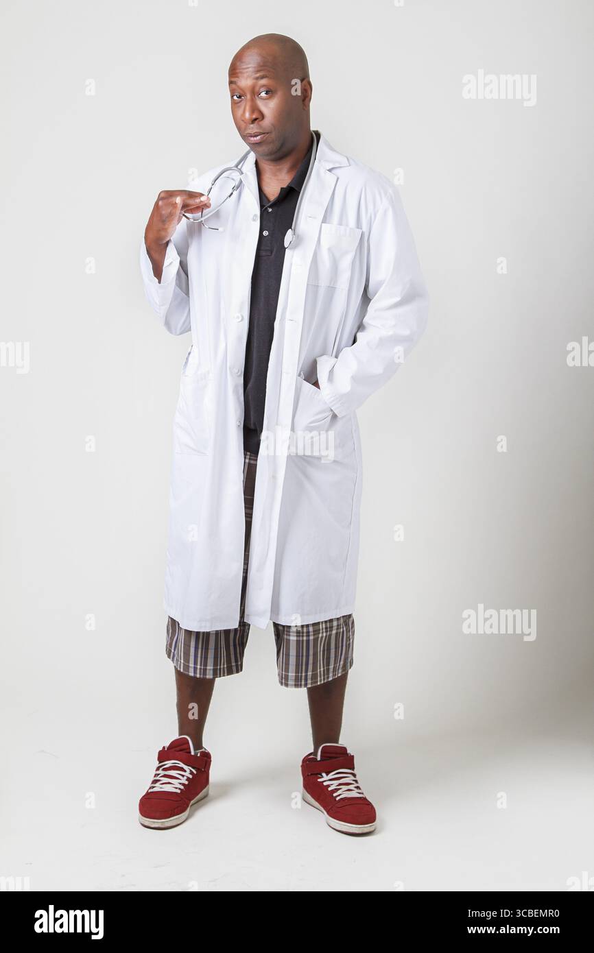 Kopf-bis-Fuß-Schuss eines kahlen schwarzen Mannes, der einen Labormantel trägt und ein Stethoskop hält Stockfoto