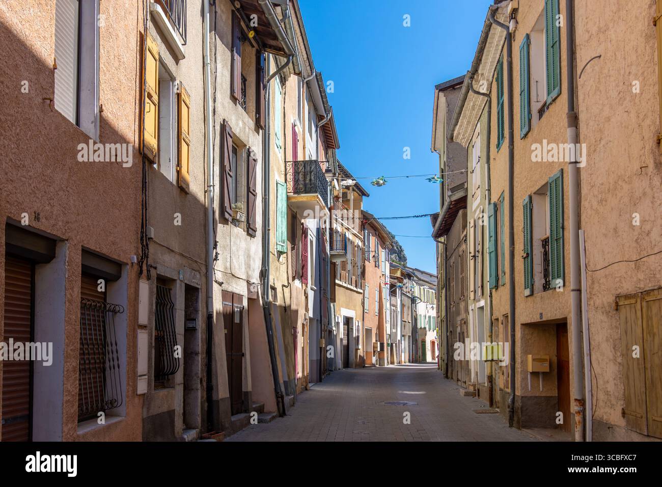 Alte traditionelle Häuser mit bunten Fassaden und Fensterläden, in einer engen Straße von Veynes, Frankreich, einer kleinen Stadt im französischen Departement Hautes-Alpes Stockfoto