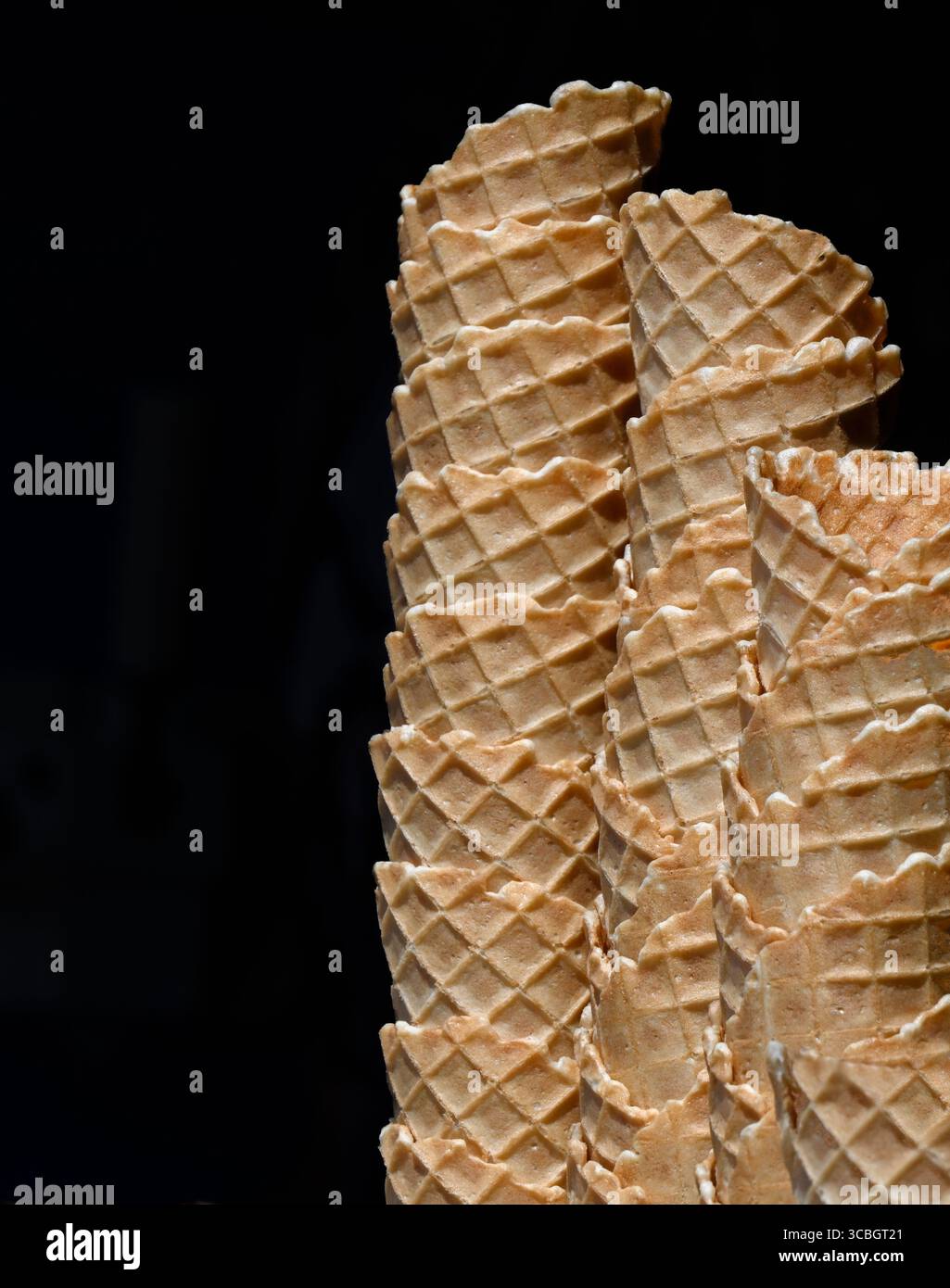 Stapel leerer Waffel-Eiskegel isoliert vor schwarzem Hintergrund Stockfoto