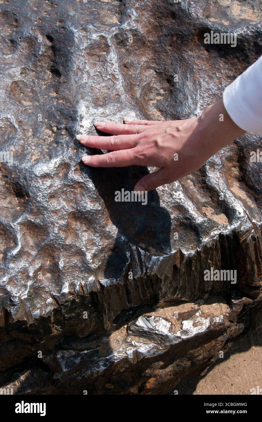 Eine Frau berührt den Hoba-Meteoriten, den größten bekannten Meteoriten der Erde, auf der Farm „Hoba West“ in der Nähe von Grootfontein in der Region Otjozondjupa in Nam Stockfoto