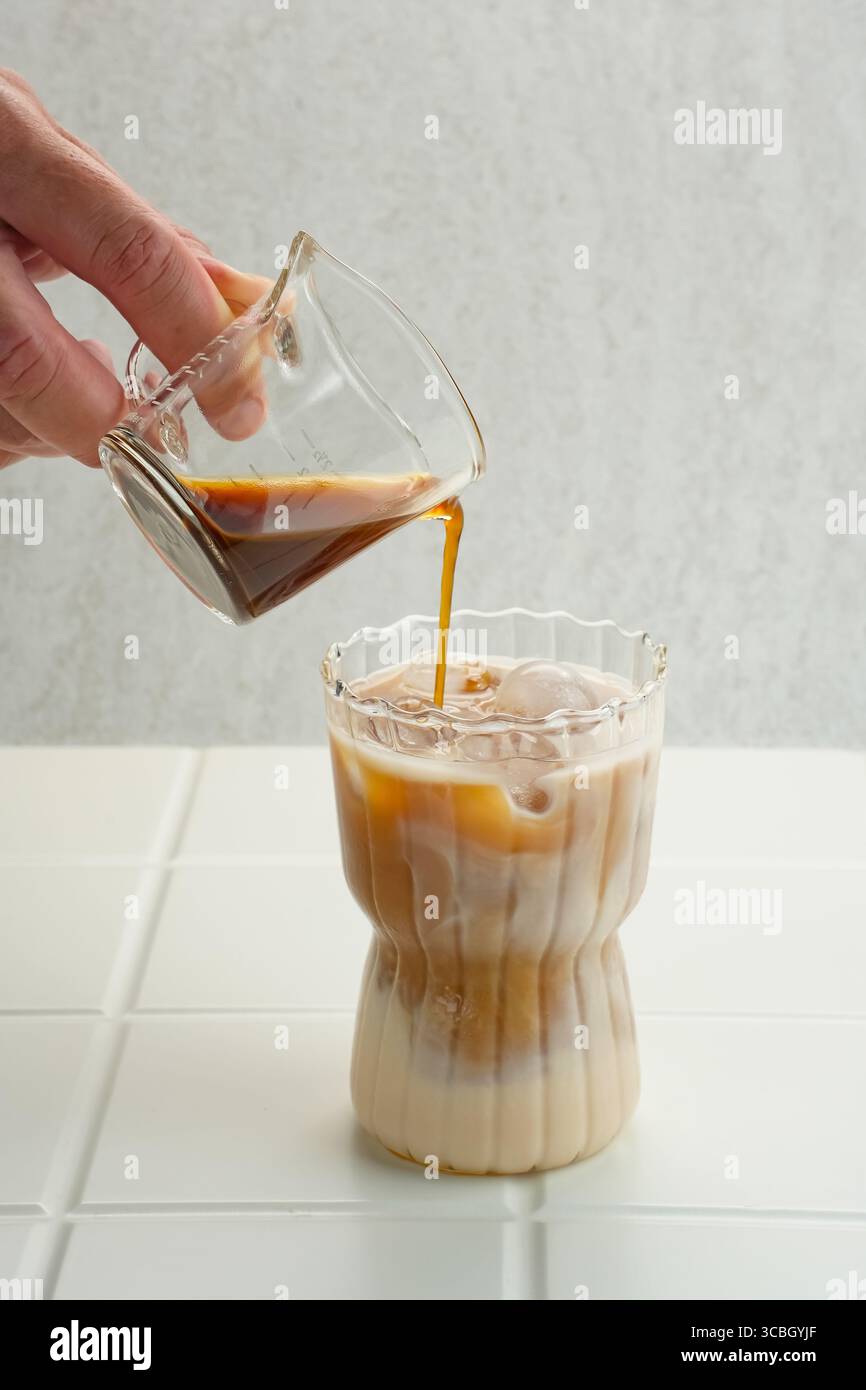 Espresso in Eiskaffee geben Stockfoto