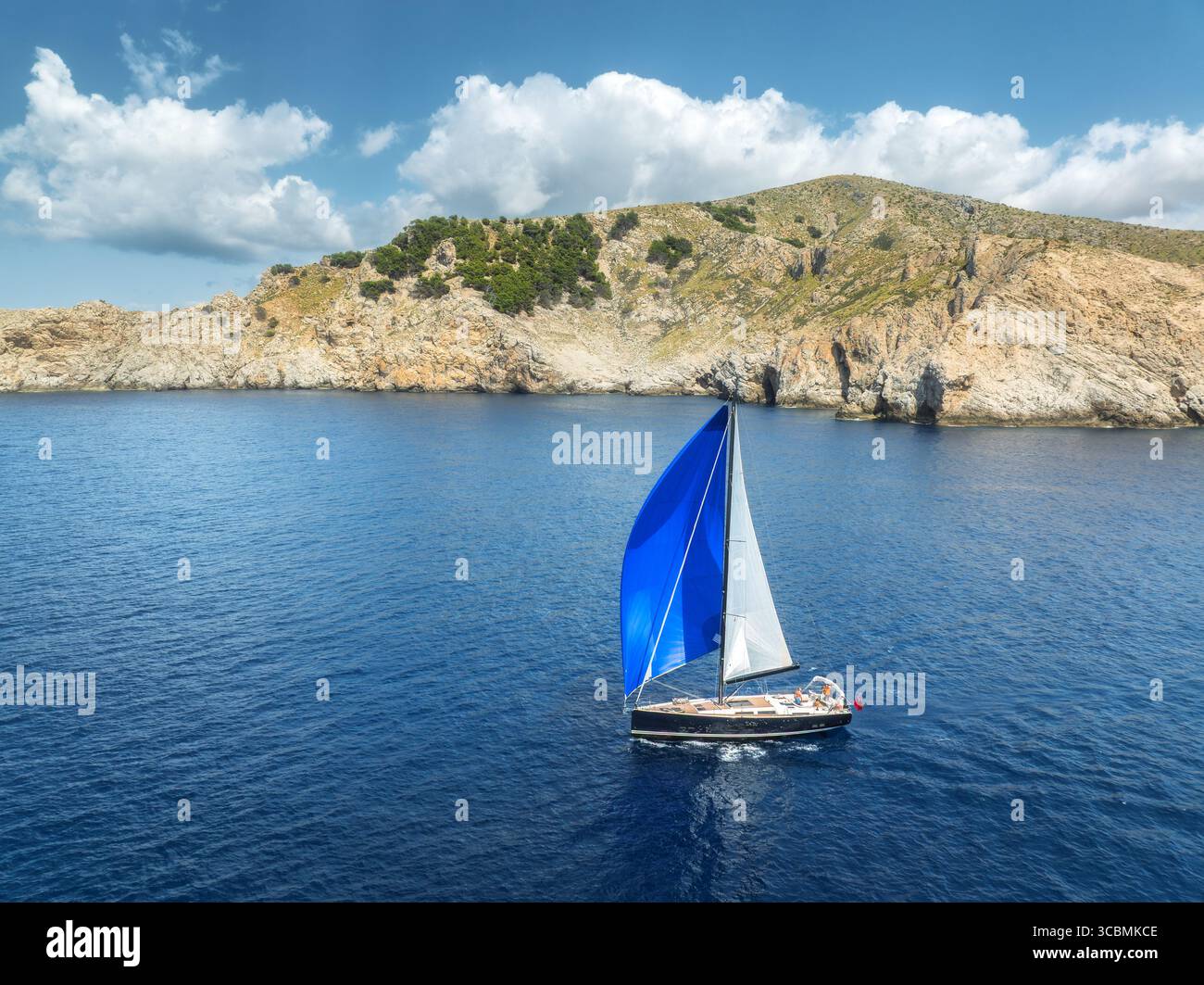 Drohnenblick auf das Segelboot mit blauem Segel auf blauem Meer Stockfoto
