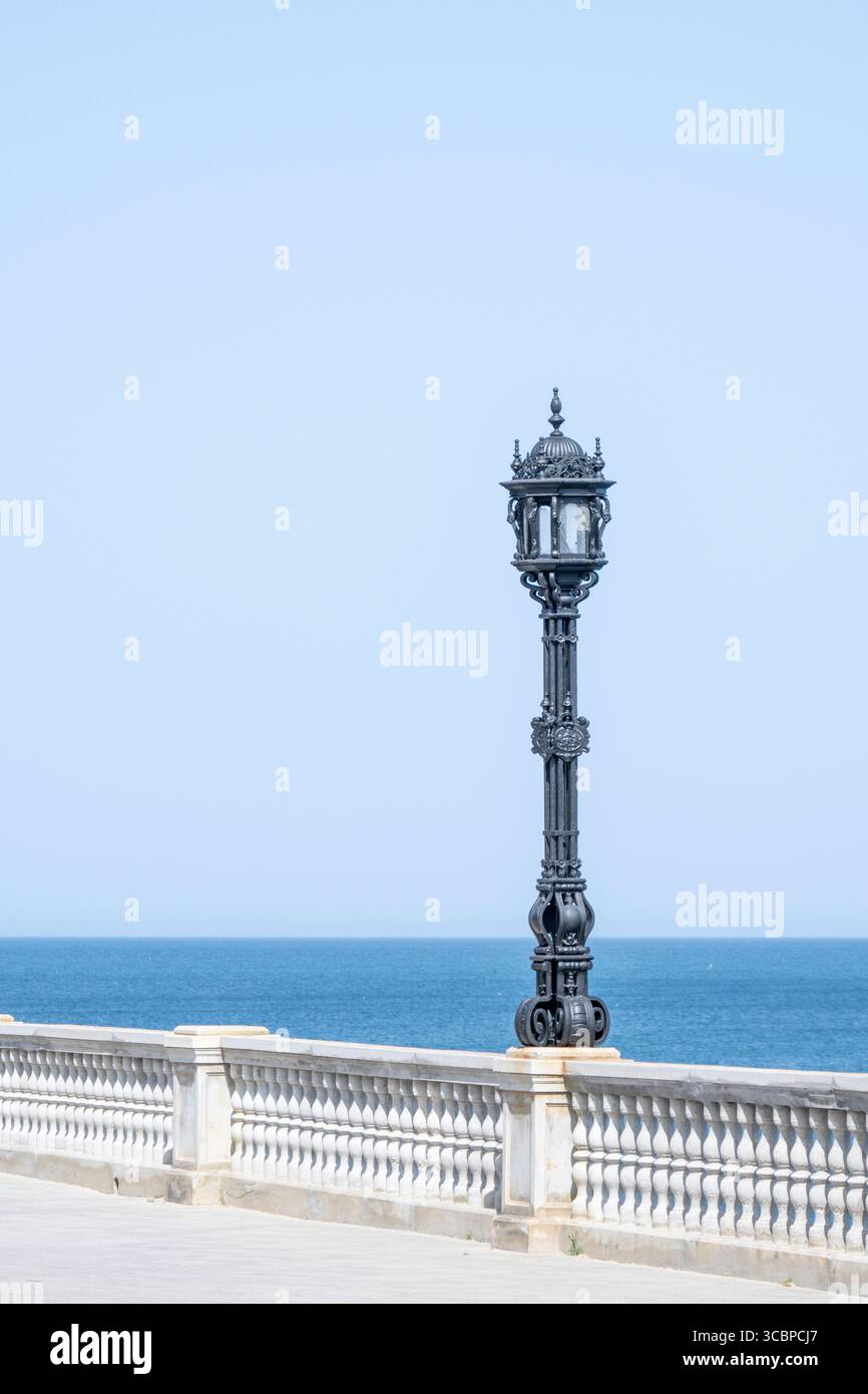 Verzierte schwarze Laternenpfahl entlang der Strandpromenade in Cádiz, Spanien, Stockfoto