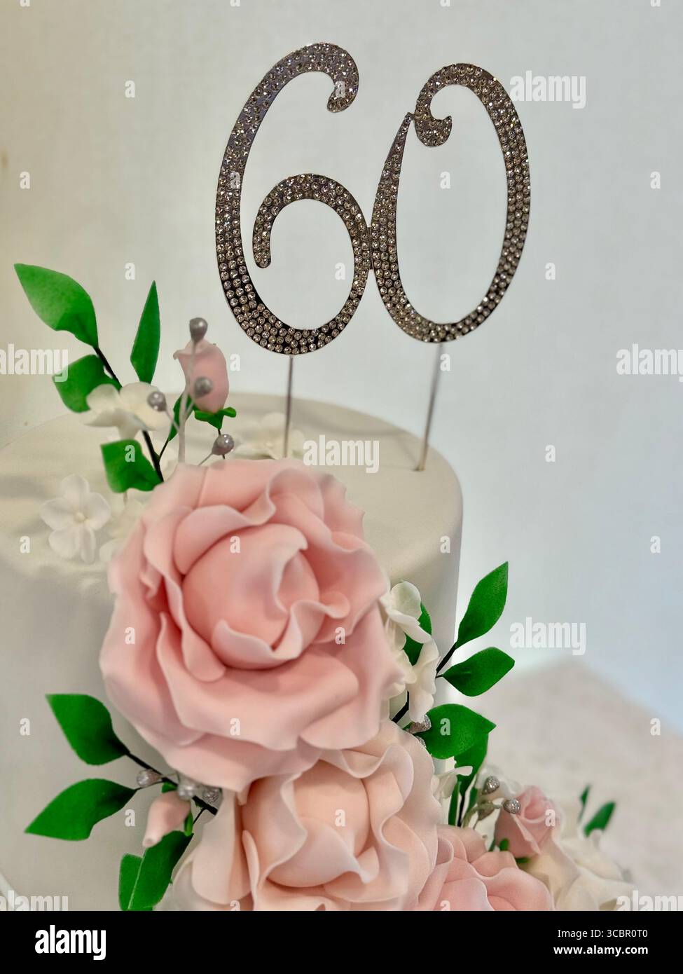 Eleganter Blumenkuchen mit „60“-Topper für Geburtstage oder Jubiläumsfeiern. Stockfoto