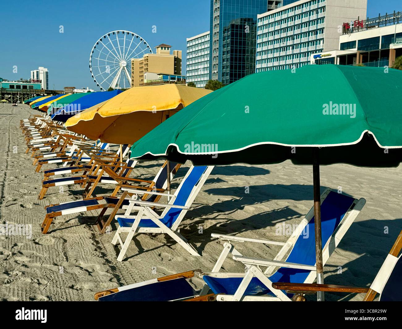 Liegen mit Sonnenschirmen, die strategisch am Myrtle Beach vor der Promenade angeordnet sind. Stockfoto
