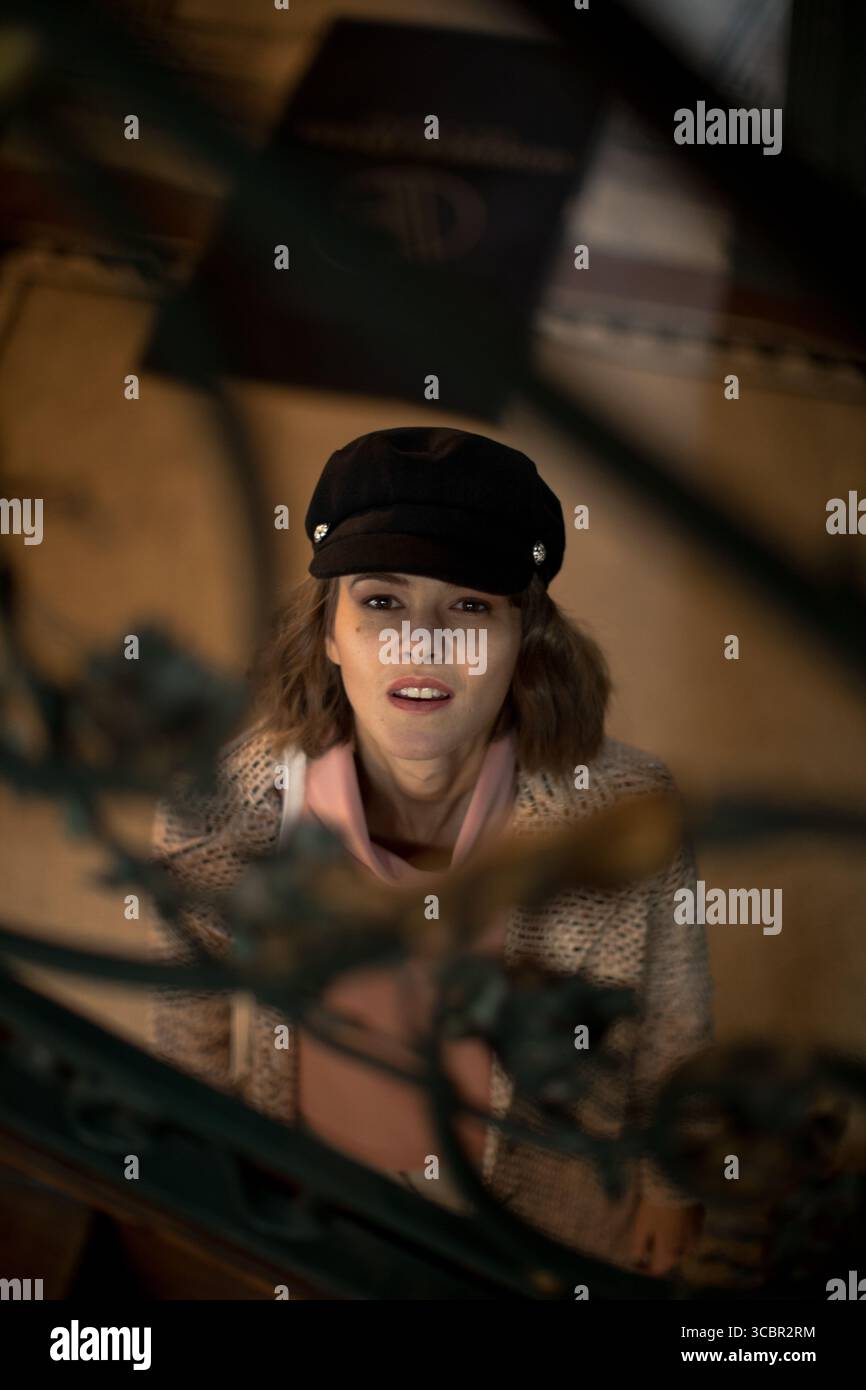 Porträt einer schönen jungen Frau, die durch das Treppengeländer in die Kamera schaut. Kreativer Headshot des Modemodells Stockfoto