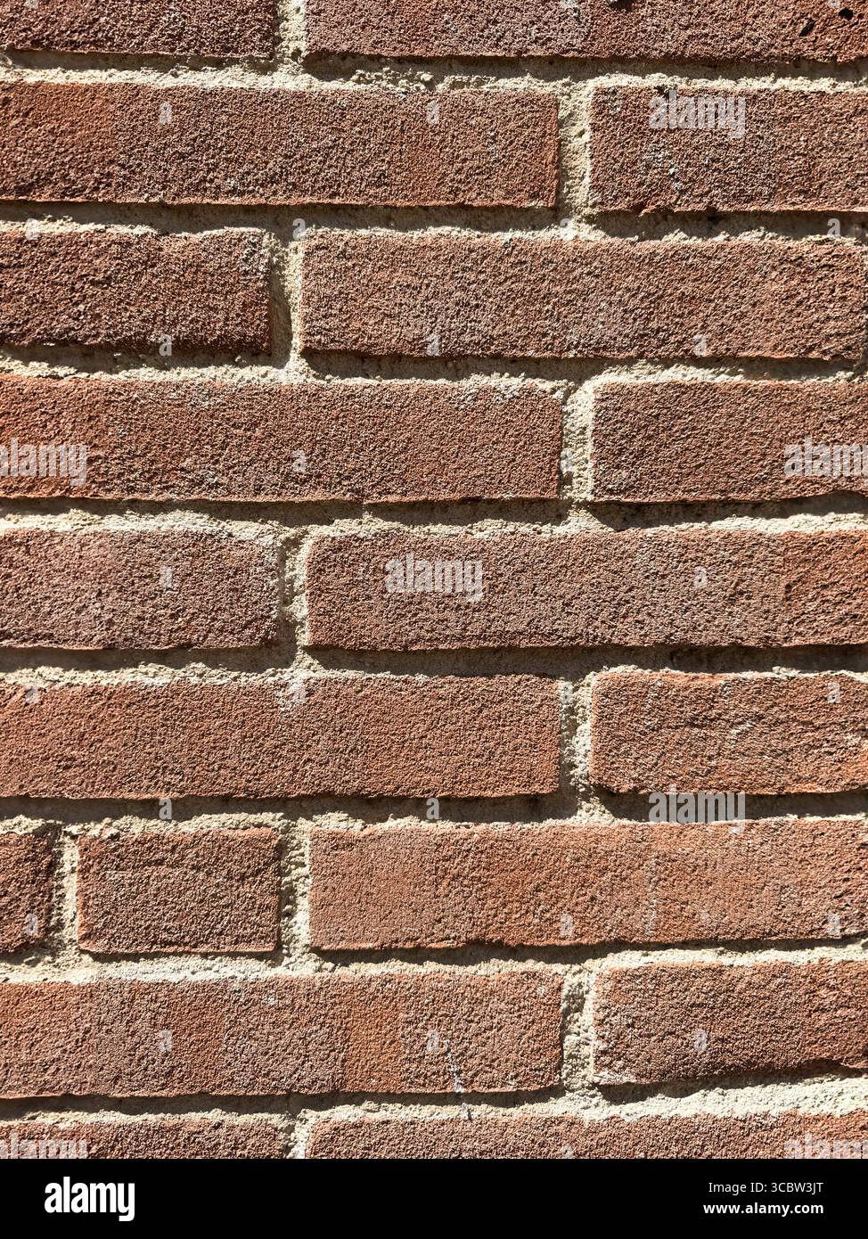 Nahaufnahme der roten Ziegelwand mit rauer Textur bei Sonnenlicht Stockfoto