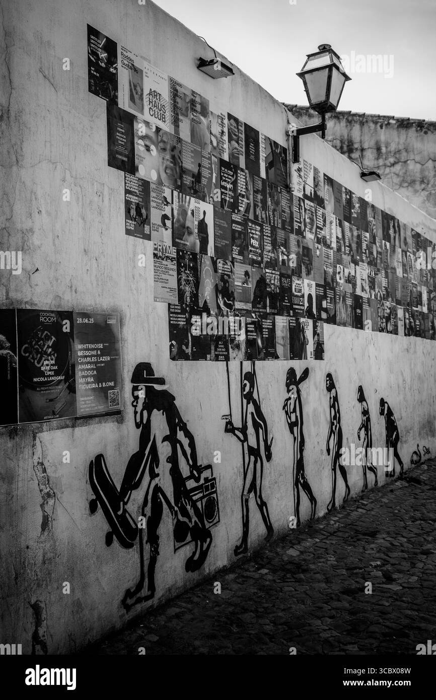 Algarve, Portugal – 2025.06.28 Street Art, die die menschliche Evolution mit Skateboards und Boomboxen unter einer Collage von Veranstaltungspostern zeigt Stockfoto