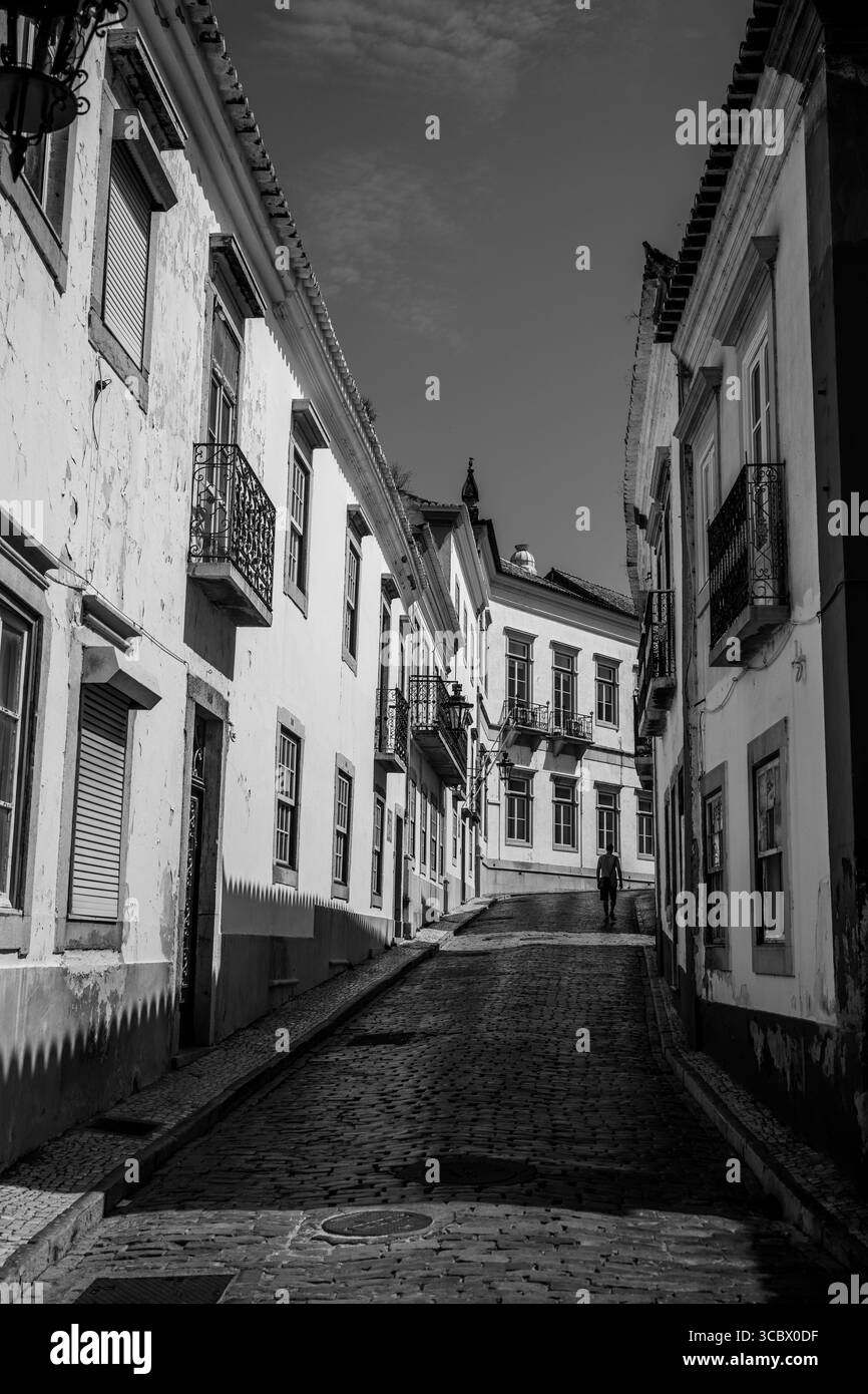 Faro, Algarve, Portugal – 2025.06.28 Eine ruhige Kopfsteinpflasterallee im historischen Zentrum von Faro, eingerahmt von traditionellen portugiesischen Gebäuden mit Schmiedewerk-iro Stockfoto