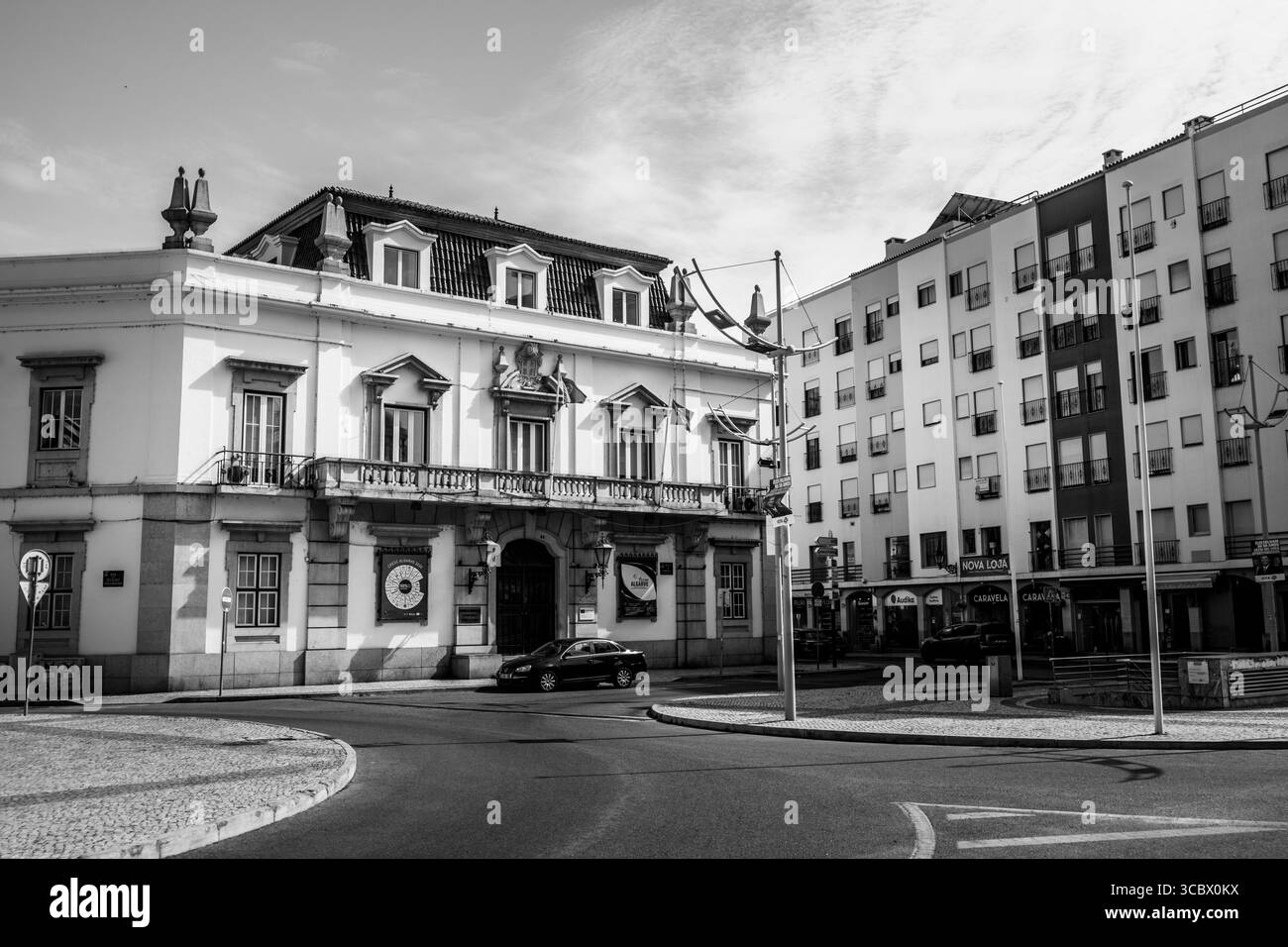 Algarve, Portugal – 2025.06.28 Ein klassisches europäisches Rathaus mit verzierten Fenstern und Fahnen steht neben modernen pastellfarbenen Wohnblöcken in einem Su Stockfoto