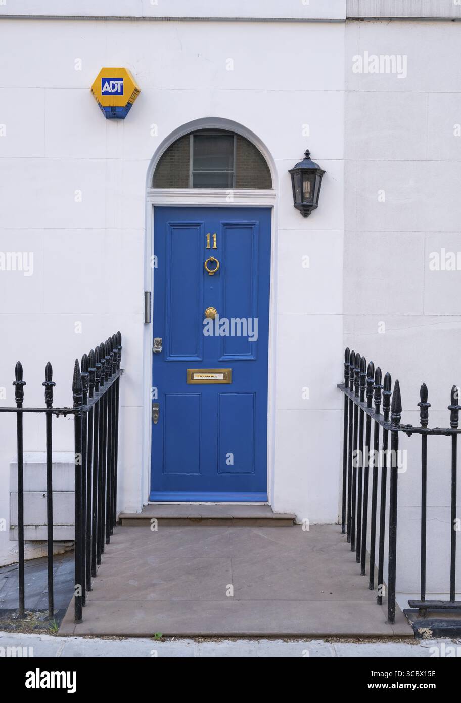 Blaue Tür mit Haus Nummer 11, flankiert von einer Laterne und einem Sicherheitsschild, umgeben von einem schmiedeeisernen Zaun, Kensington, London, England, Vereinigtes Königreich Stockfoto
