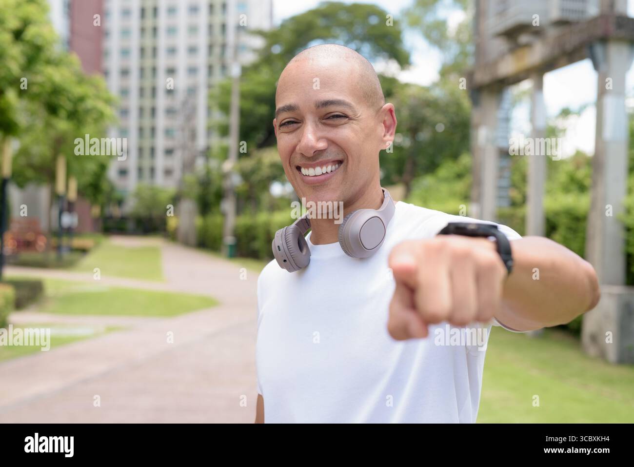 Glatze Latin man spaziert in der Stadt oder im Park und genießt die Bewegung im Freien. Fängt selbstbewussten Wellness-Lebensstil, aktive Gewohnheiten und gesunde Sommer Urban ein Stockfoto
