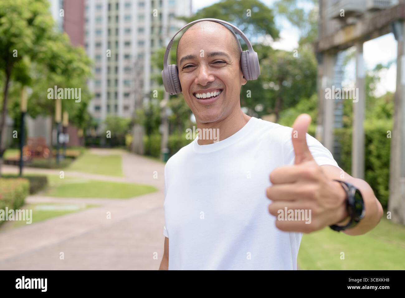 Glatze Latin man spaziert in der Stadt oder im Park und genießt die Bewegung im Freien. Fängt selbstbewussten Wellness-Lebensstil, aktive Gewohnheiten und gesunde Sommer Urban ein Stockfoto